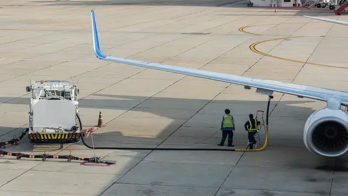 Image of two workers filling a plane with fuel