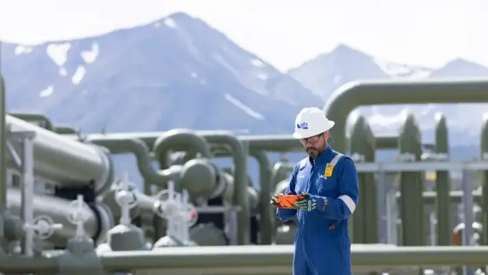SLB worker infront of a geothermal factory with a mountain in the background